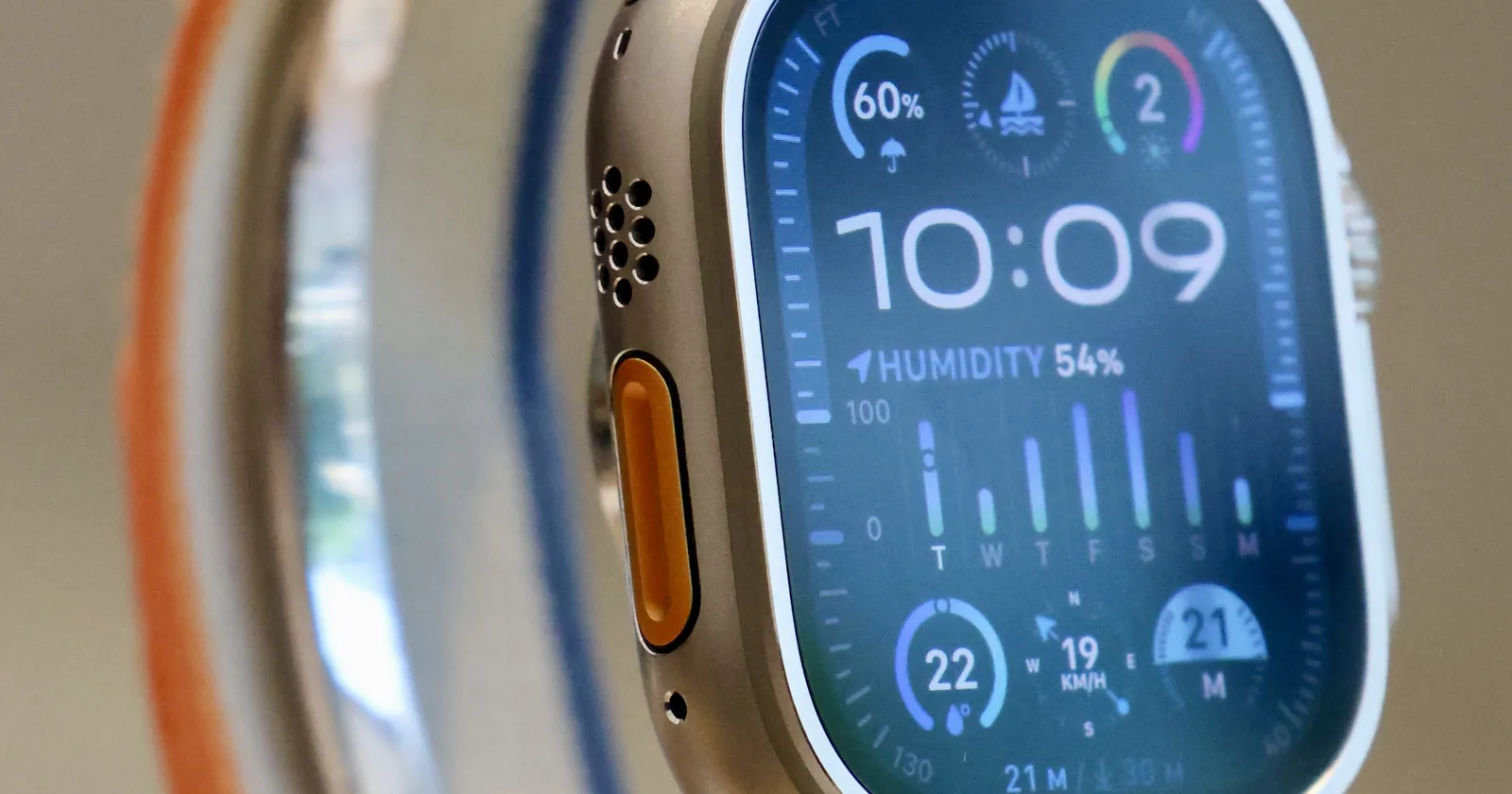 Close-up of an Apple Watch Ultra 2 on a store display, titanium case with the orange Action button