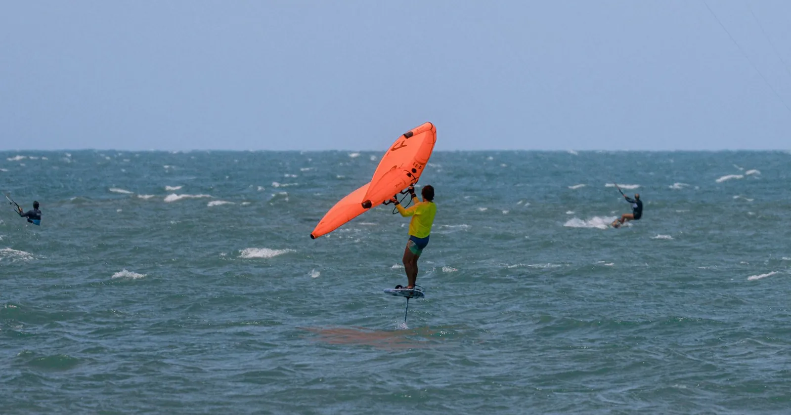 Wing foiling gear laid out on a beach