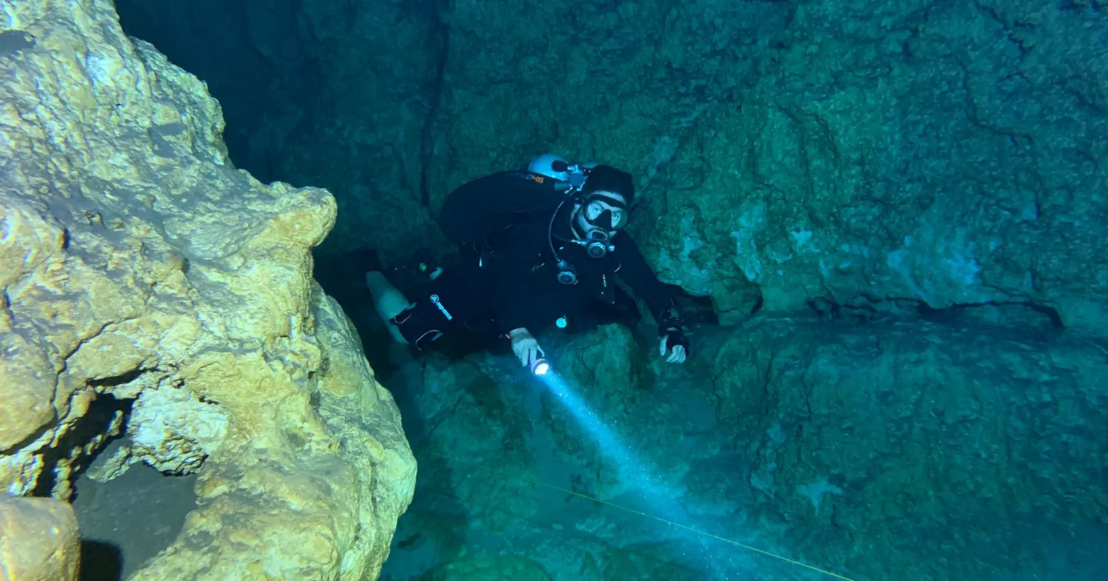 Diver descending into deeper blue water where a torch earns its place