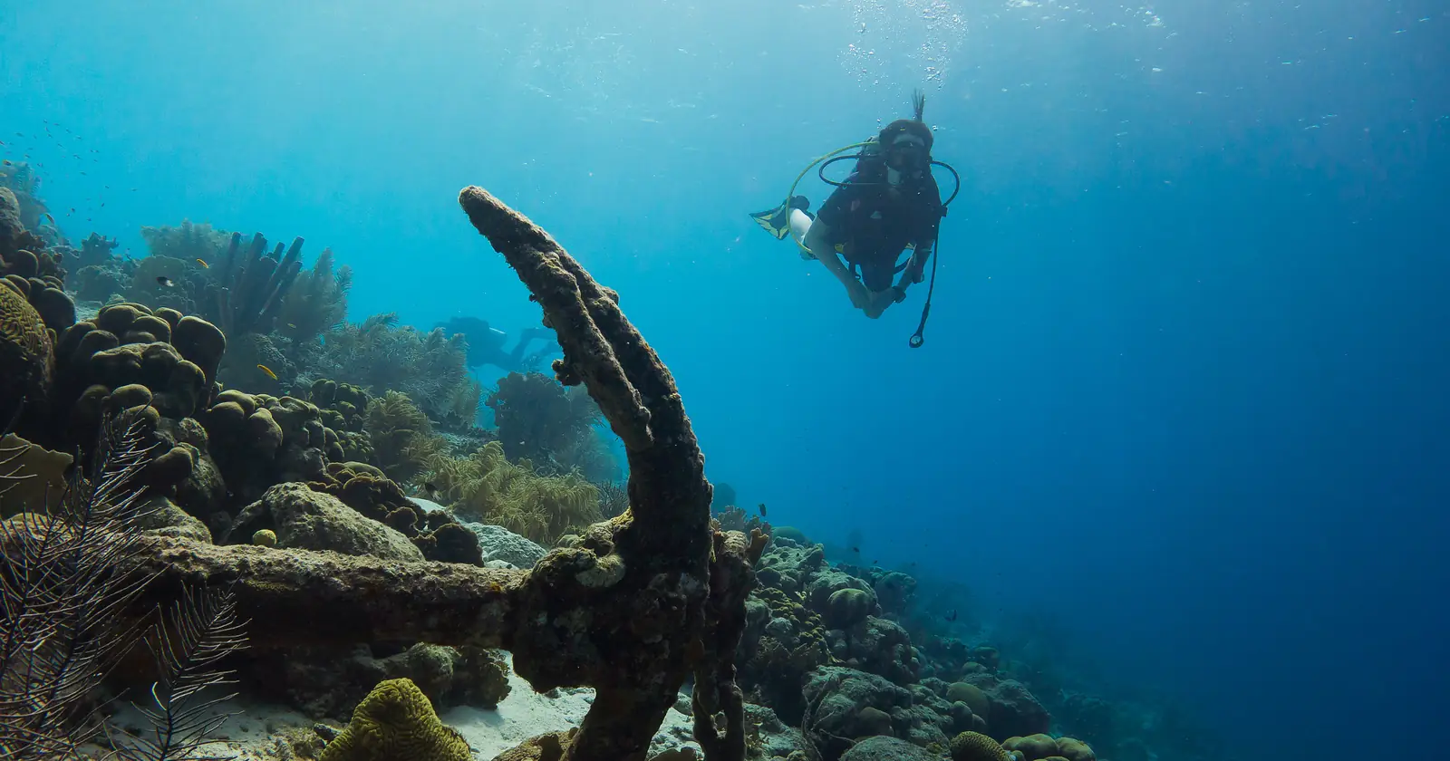Scuba diver over a Bonaire reef beside an old anchor