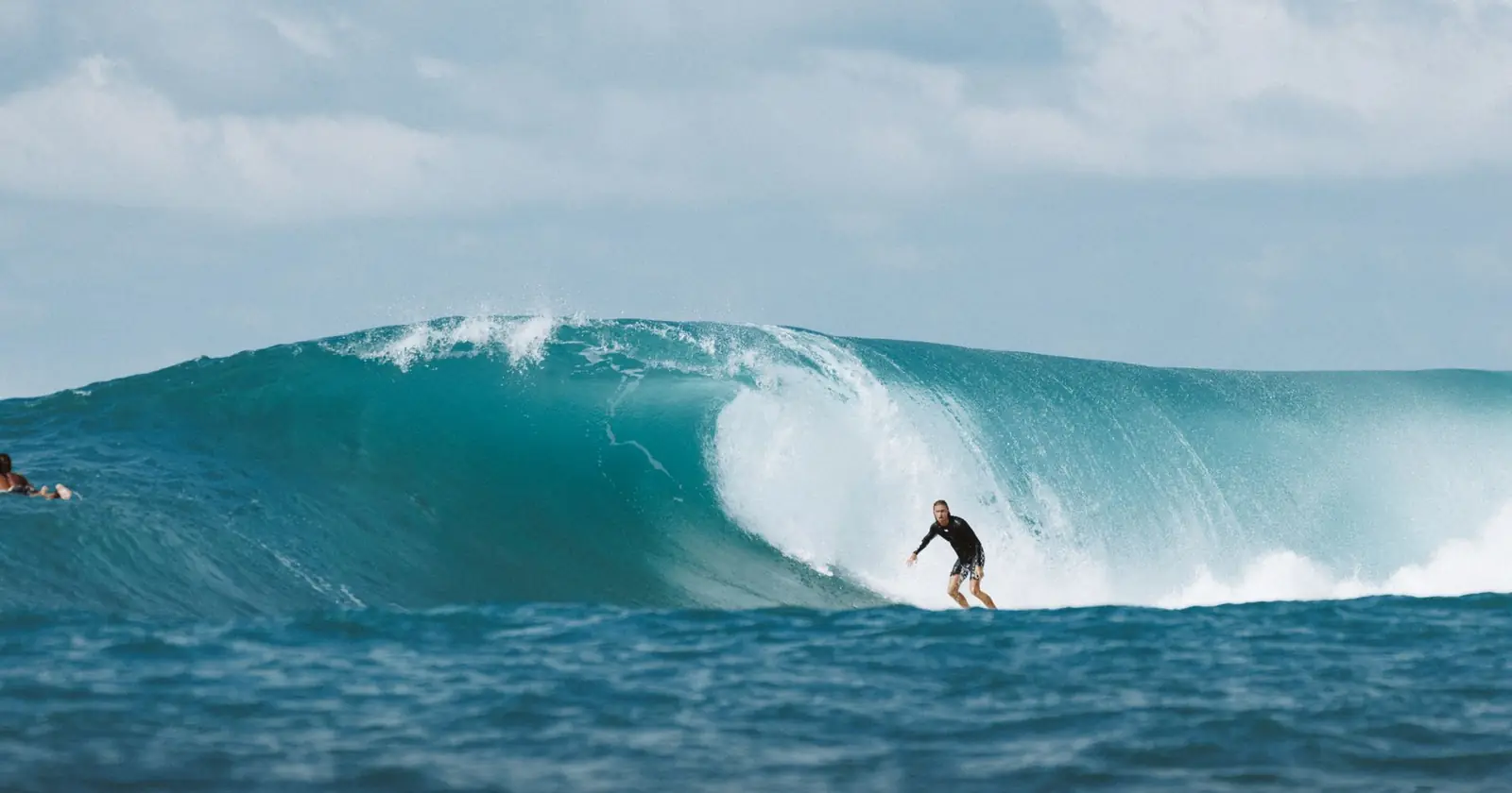 Surfer riding a massive ocean wave in Bali, capturing the th