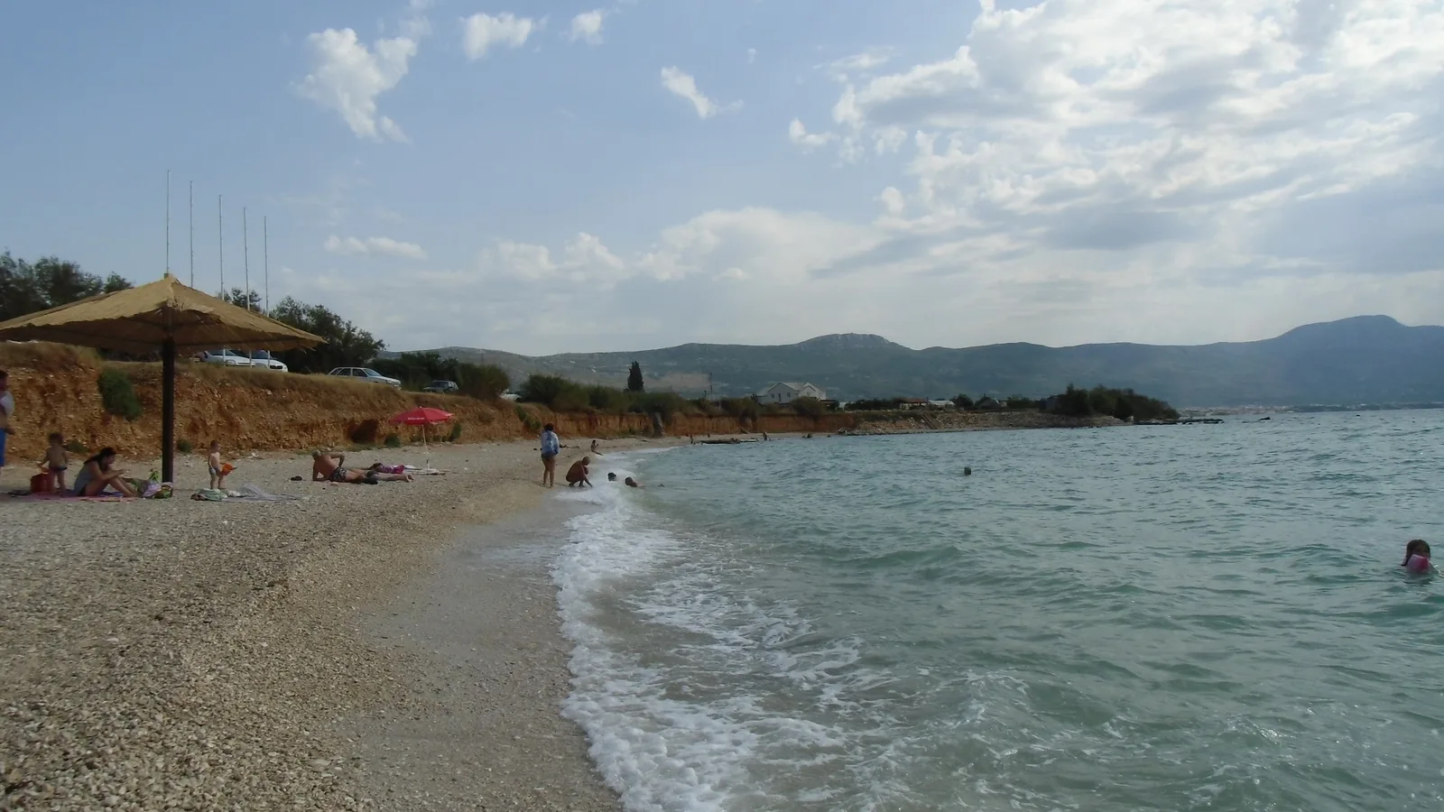 The pebble beach at Divulje near Split, Croatia, with the hills of Kastela behind a calm bay