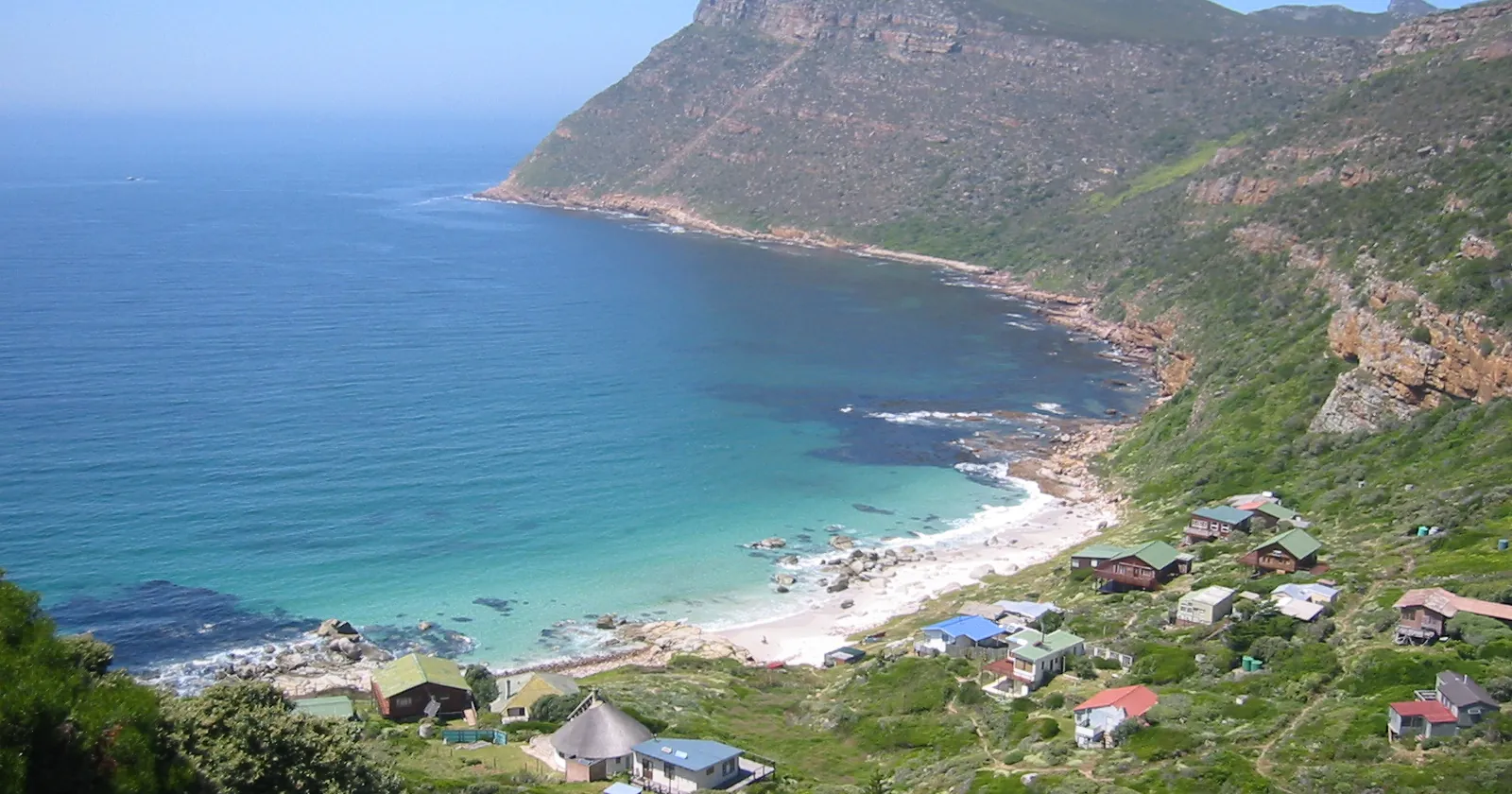 Smitswinkel Bay in False Bay on the Cape Peninsula, seen from the hillside above its cottages, with the scuttled frigates of Cape Town diving lying off the bay