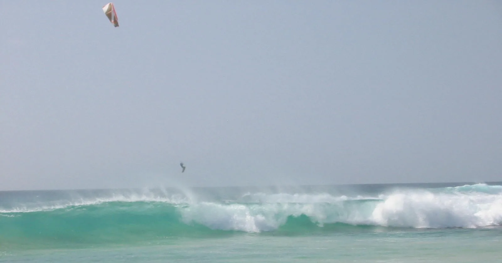Kitesurfer jumping above a breaking wave at Ponta Preta on Sal, the expert wave spot