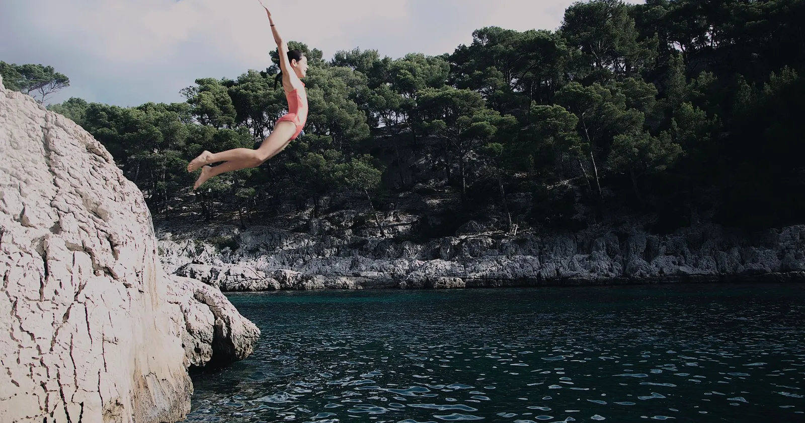 Coasteerers scrambling and jumping along a rocky coastline