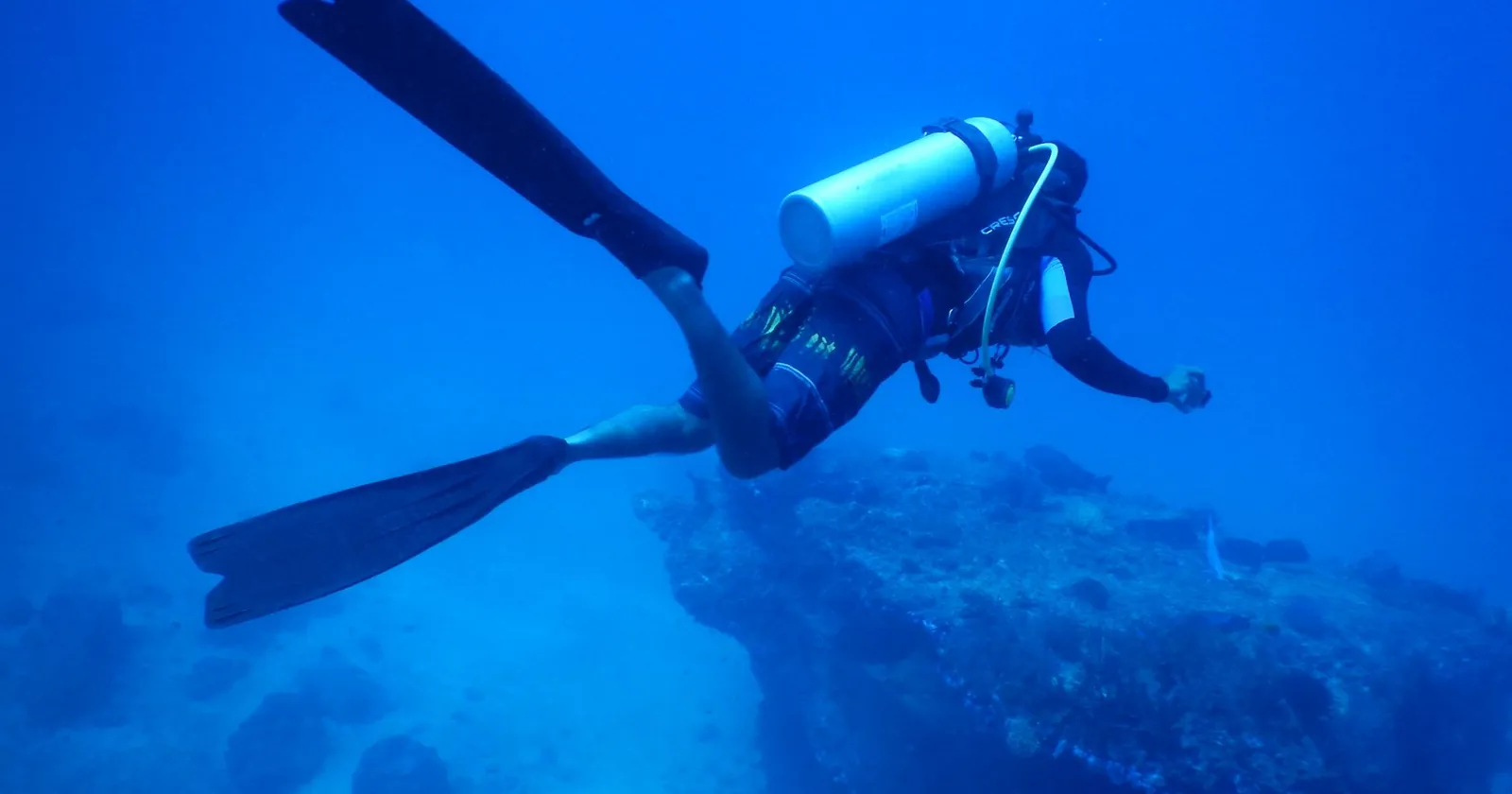 Scuba diver descending on a reef, illustrating dive insurance depth limits