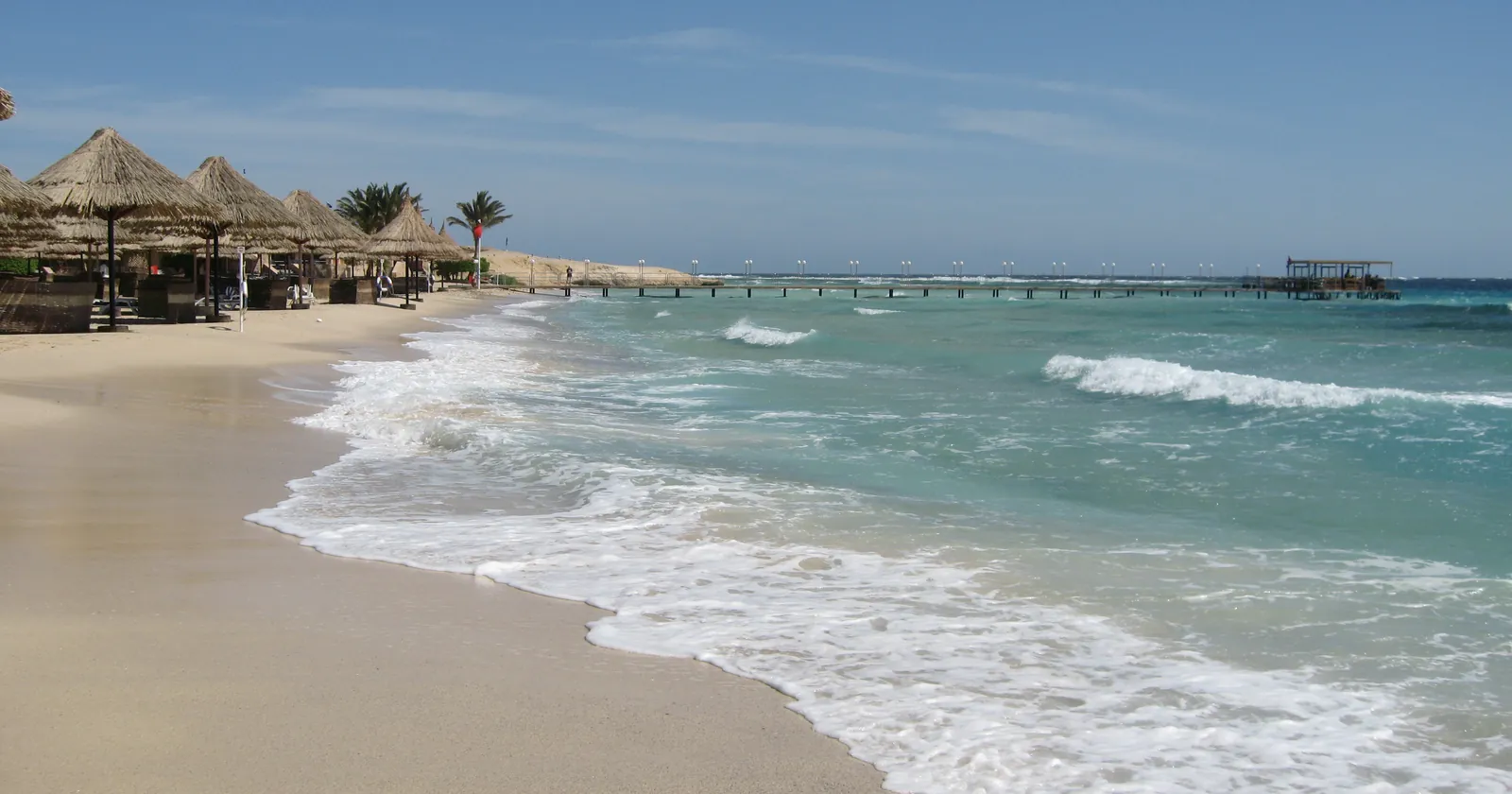 Beach on the El Quseir coast with a long jetty running out over the reef flat to the reef edge, where the waves break, the usual way into the water for El Quseir diving