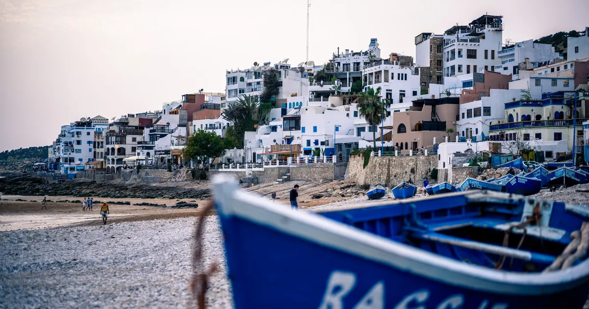 Taghazout surf village above the beach with blue fishing boats in front