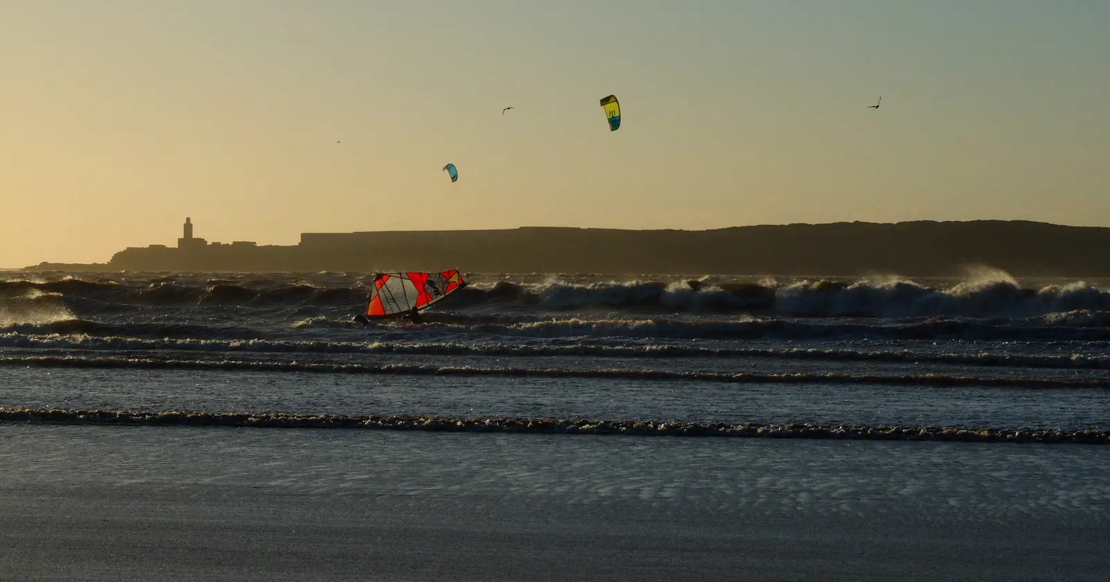 Kitesurfers and a windsurfer on Essaouira bay in the evening wind