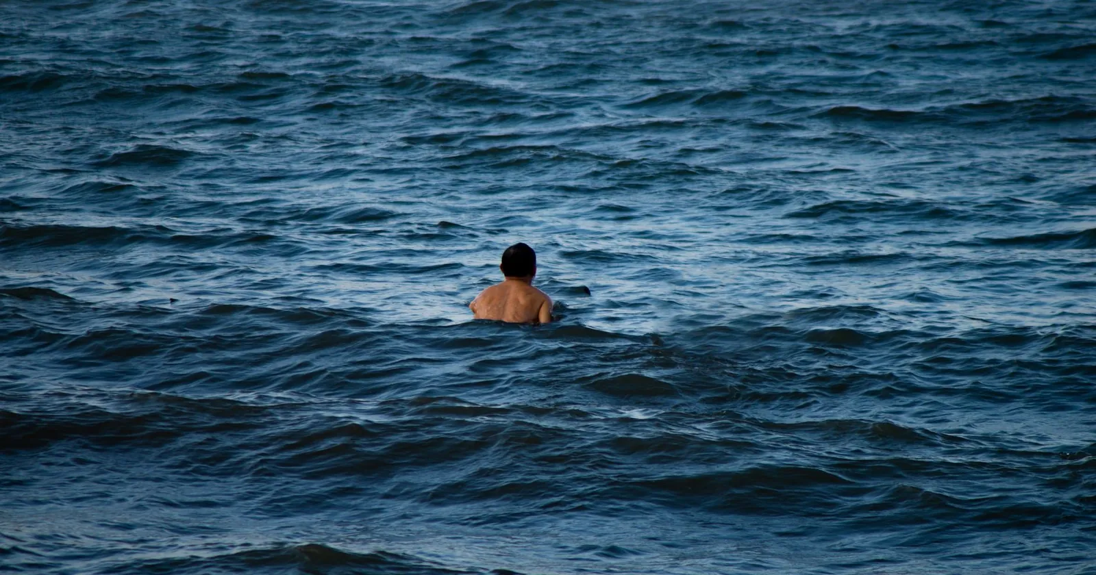 Bodysurfer streamlined and angling across a wave face