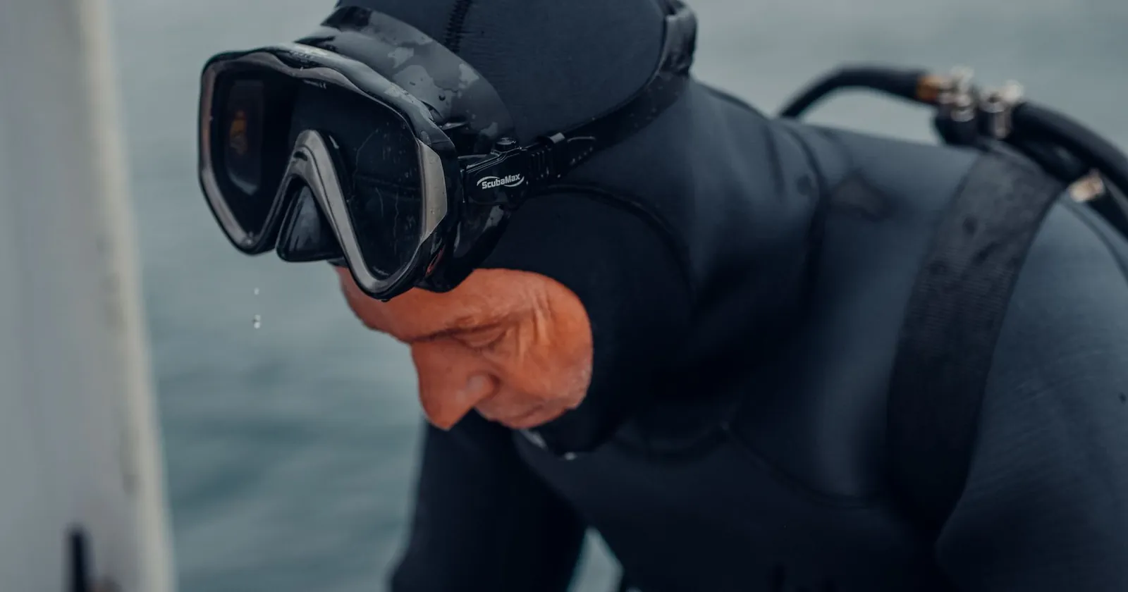 Diver in a wetsuit with mask, fins, wrist dive computer and an underwater camera