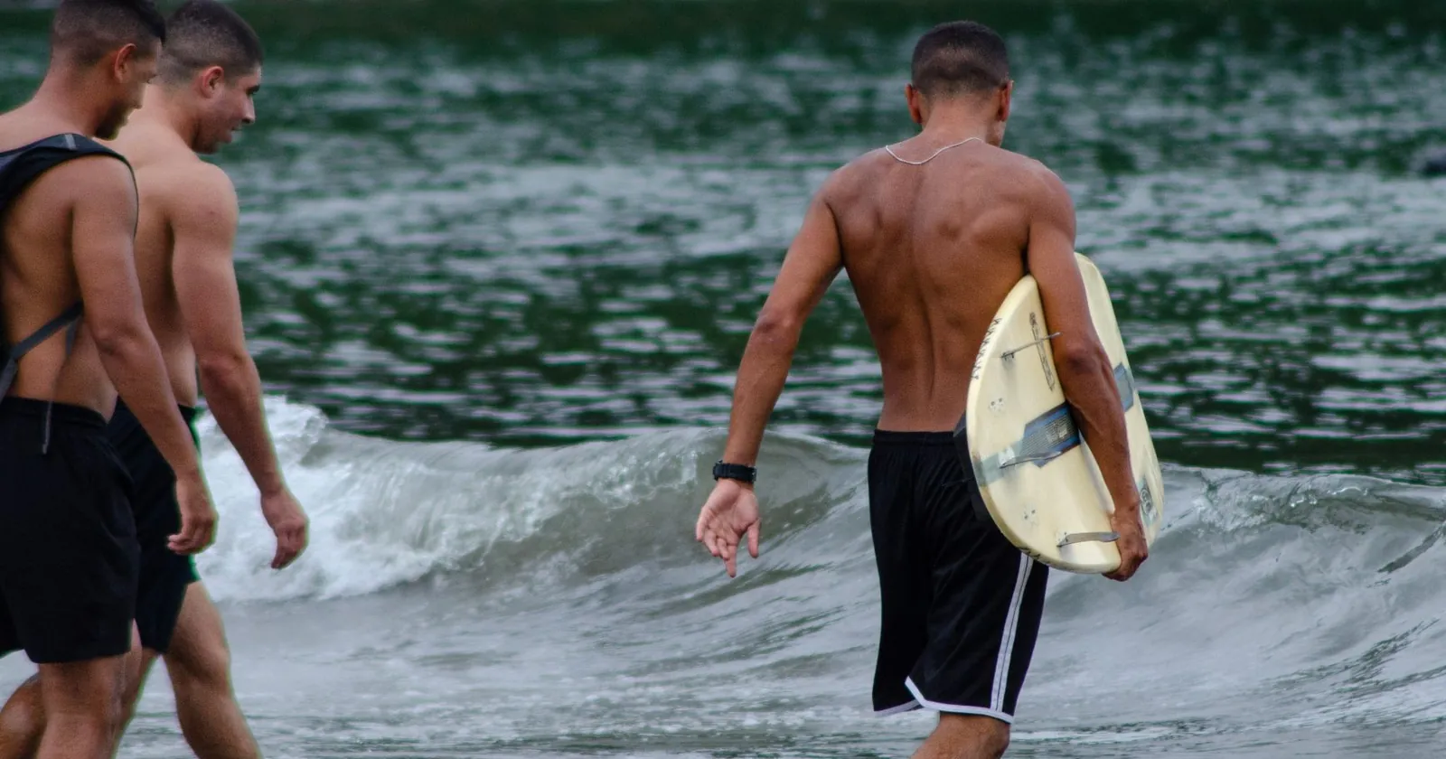 Skimboarder gliding across thin water on a beach