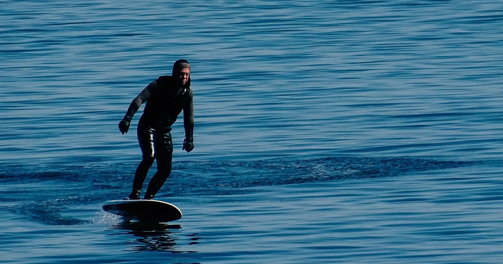 Beginner learning to balance on a foil board close to the surface