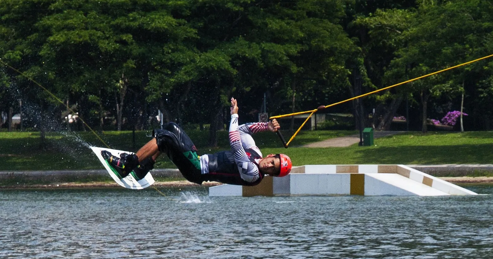 Wakeboarder being pulled up out of the water at a cable park
