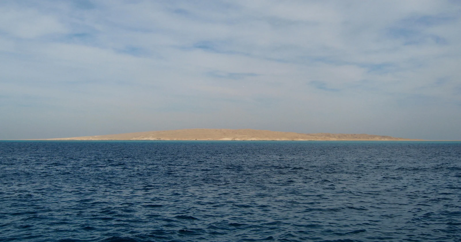 Giftun Island off Hurghada seen from the water, with the pale shallow reef shelf between the island and deep blue open sea