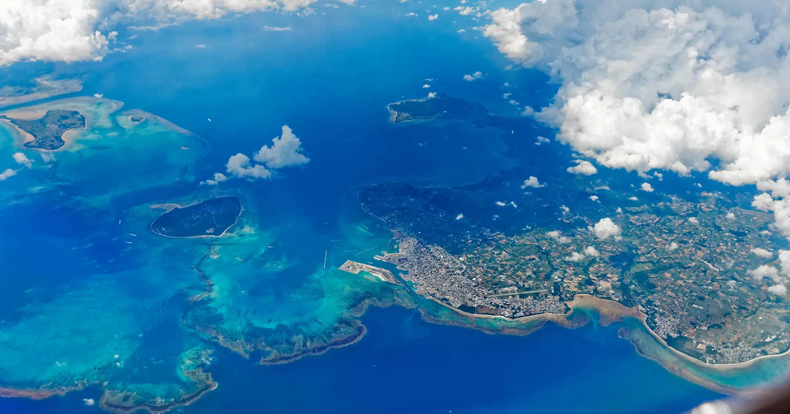 Aerial view of Ishigaki diving country: Ishigaki city and airport shore with the Sekisei Lagoon reefs, Taketomi and Kohama islands to the west