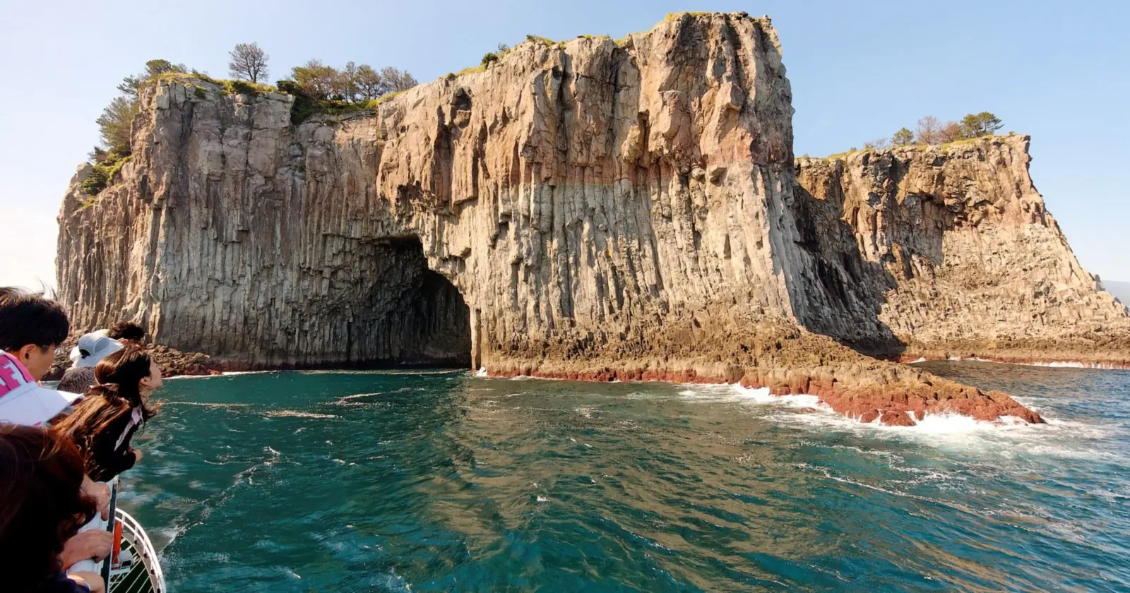 The columnar cliffs and sea cave of Beomseom, one of the Seogwipo islets at the center of Jeju diving, seen from a boat out of Seogwipo