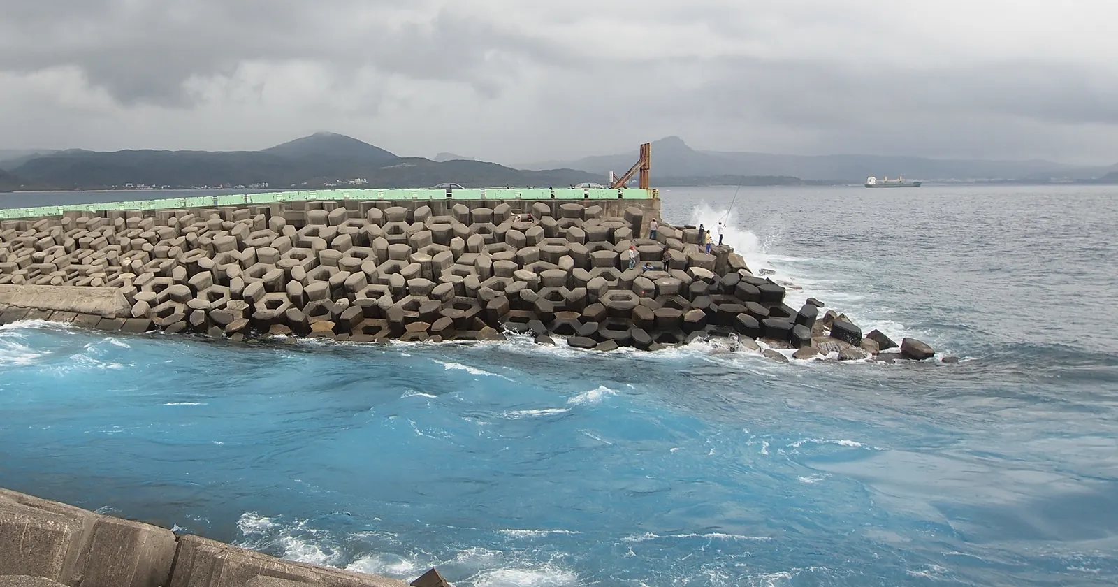 Turbulent blue cooling water flowing past a breakwater of concrete blocks at the Maanshan plant outlet on Nanwan Bay, a Kenting diving site
