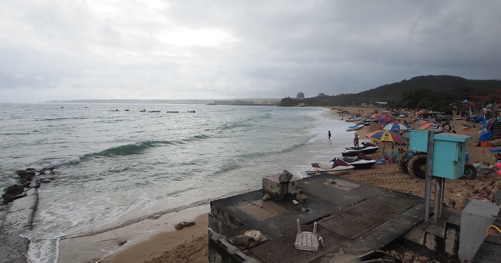 Nanwan Bay beach with jet skis on the sand and the domes of the Maanshan nuclear power plant on the far headland, the bay where much Kenting diving happens
