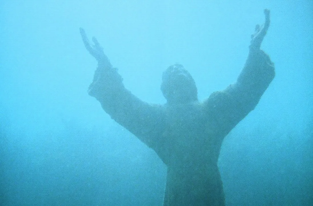 The bronze Christ of the Abyss statue with raised arms in blue water at Key Largo Dry Rocks, the best-known Key Largo diving site, in 2007
