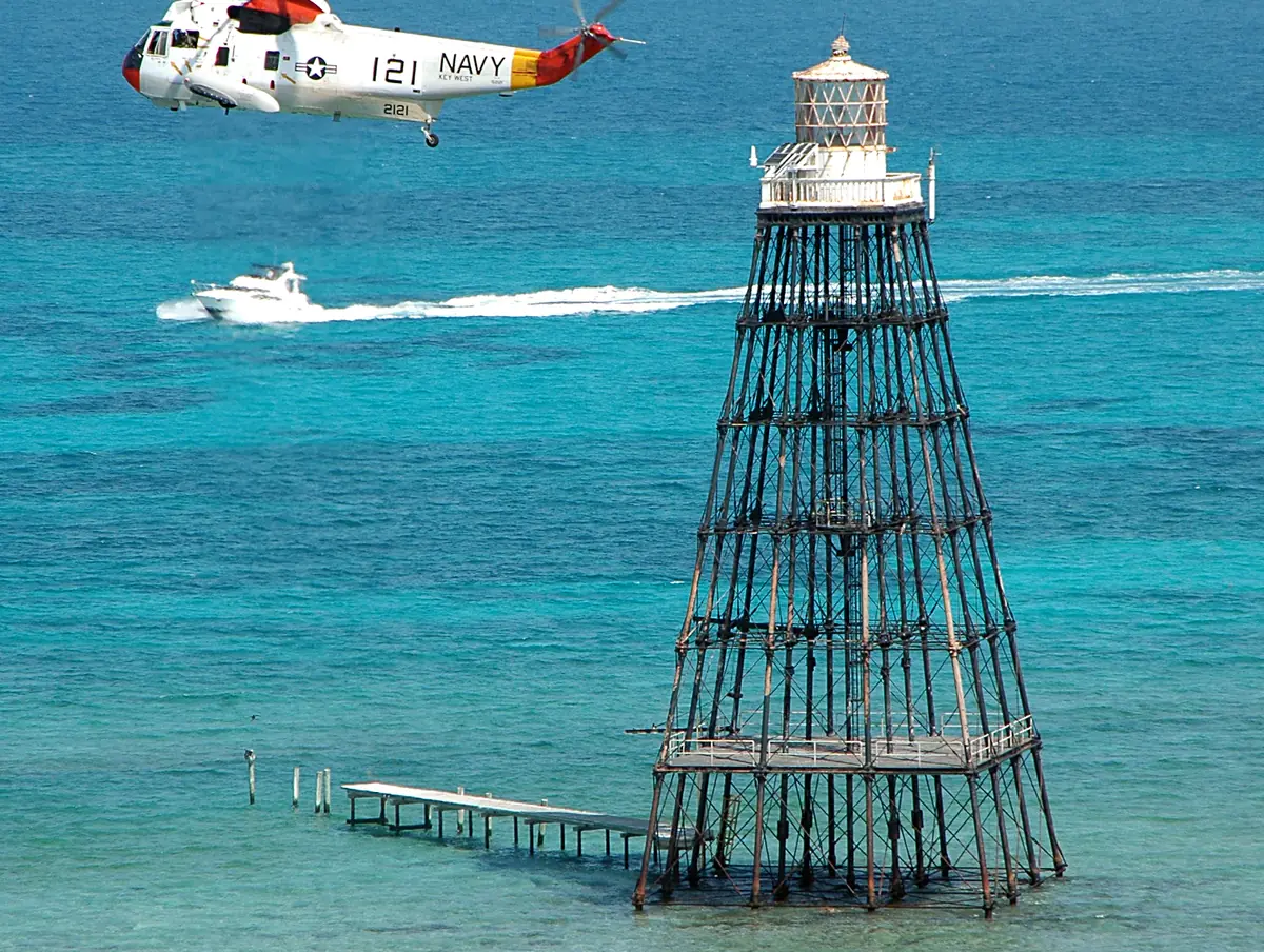 Sand Key Lighthouse standing on the shallow reef flat of the Sand Key preservation area, a staple of Key West diving, with a Navy helicopter overhead in 2005