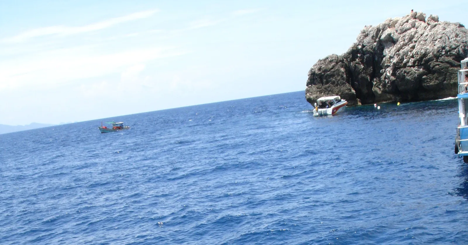 Sail Rock, the granite pinnacle between Koh Phangan and Koh Tao, with a speedboat beside it, the main site for Koh Phangan diving day trips