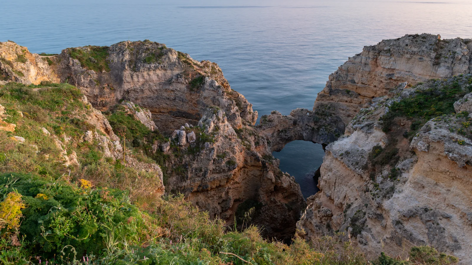 The sea arch and cliffs at Ponta da Piedade near Lagos, Portugal, at dusk with calm water