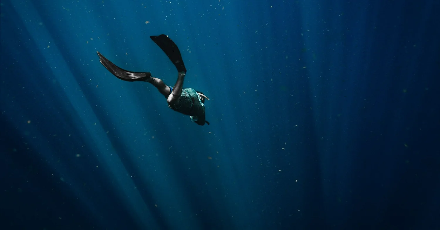 Steep volcanic rock dropping straight into deep blue Atlantic water off a south-coast island shoreline