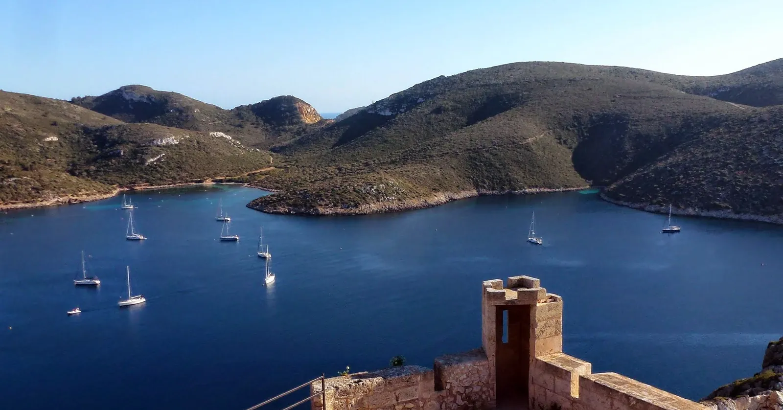 Boats moored in the bay below the castle walls in Cabrera National Park, the park south of the island where Mallorca diving needs the park’s own authorization