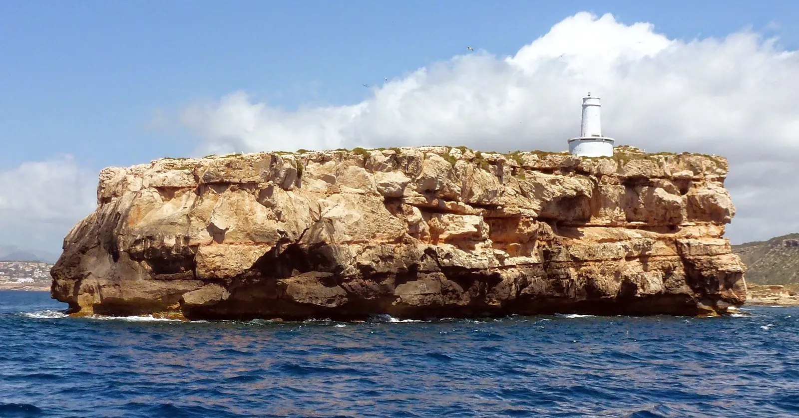 The Illa del Toro off Calvià with its white light tower, the islet at the center of Mallorca diving in the Ponent reserve, seen from a boat
