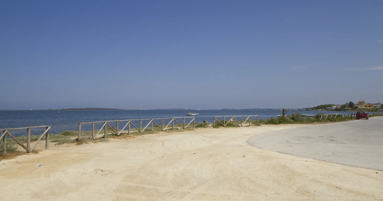 The shallow lagoon of Lo Stagnone near Marsala in Sicily, with the low outline of Isola Grande on the horizon and a sandy shore in the foreground