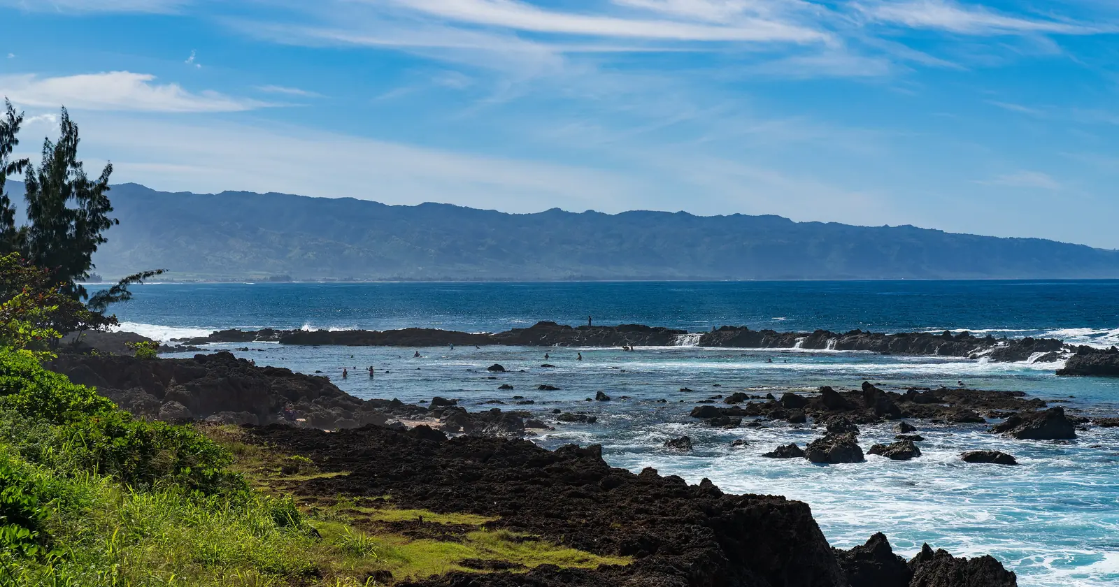 Lava rock shoreline at Pupukea Beach Park and Shark's Cove on Oahu's North Shore in January, with white water breaking over the outer reef, a site for Oahu diving in summer