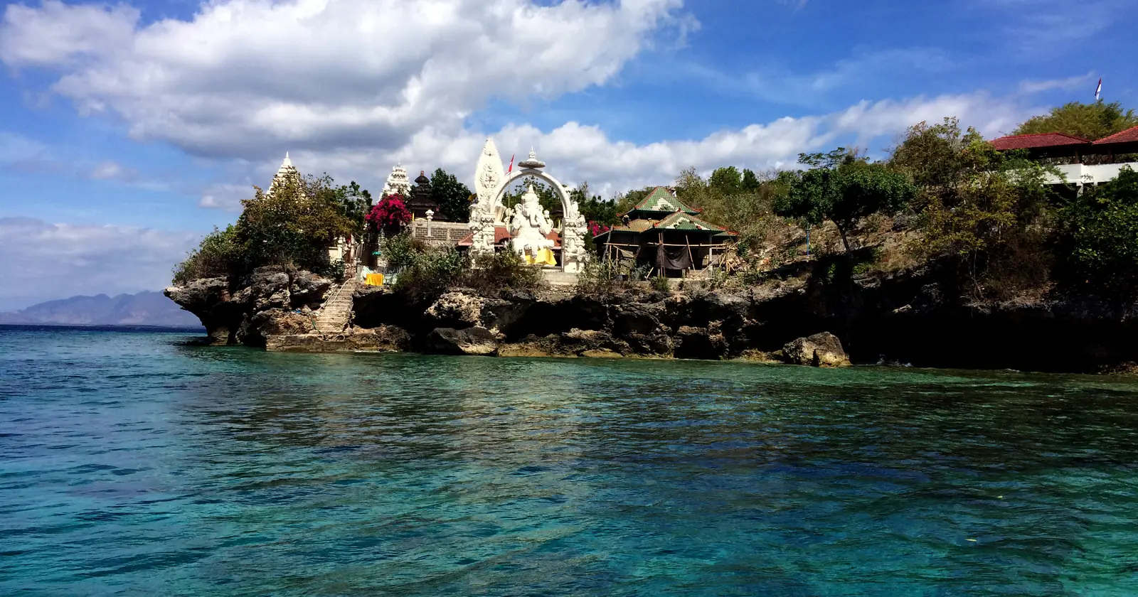 A Hindu temple gate on the rocky shore of Menjangan Island seen from the clear shallow water that Pemuteran diving boats cross to reach it