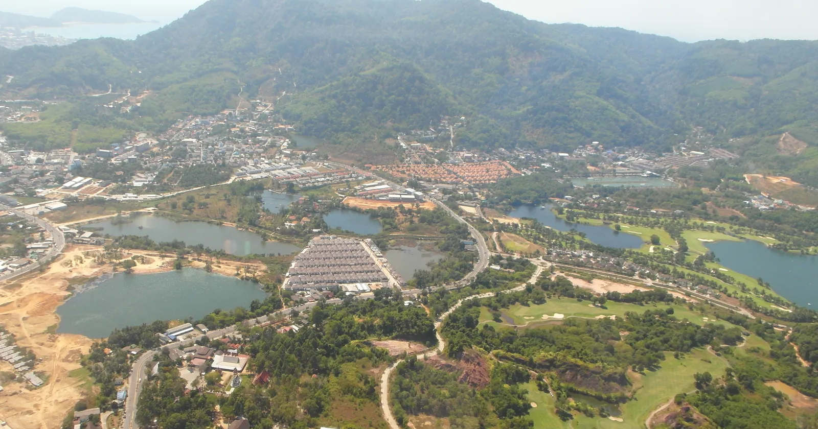 Kathu from the air, the inland Phuket district where Phuket Wake Park's cable lake sits, with Patong Bay beyond the ridge