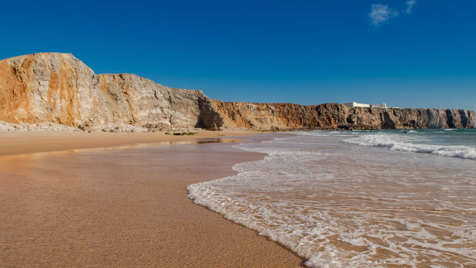 Praia do Tonel at Sagres, Portugal, with the cliffs and the fortress headland behind the breaking shorebreak