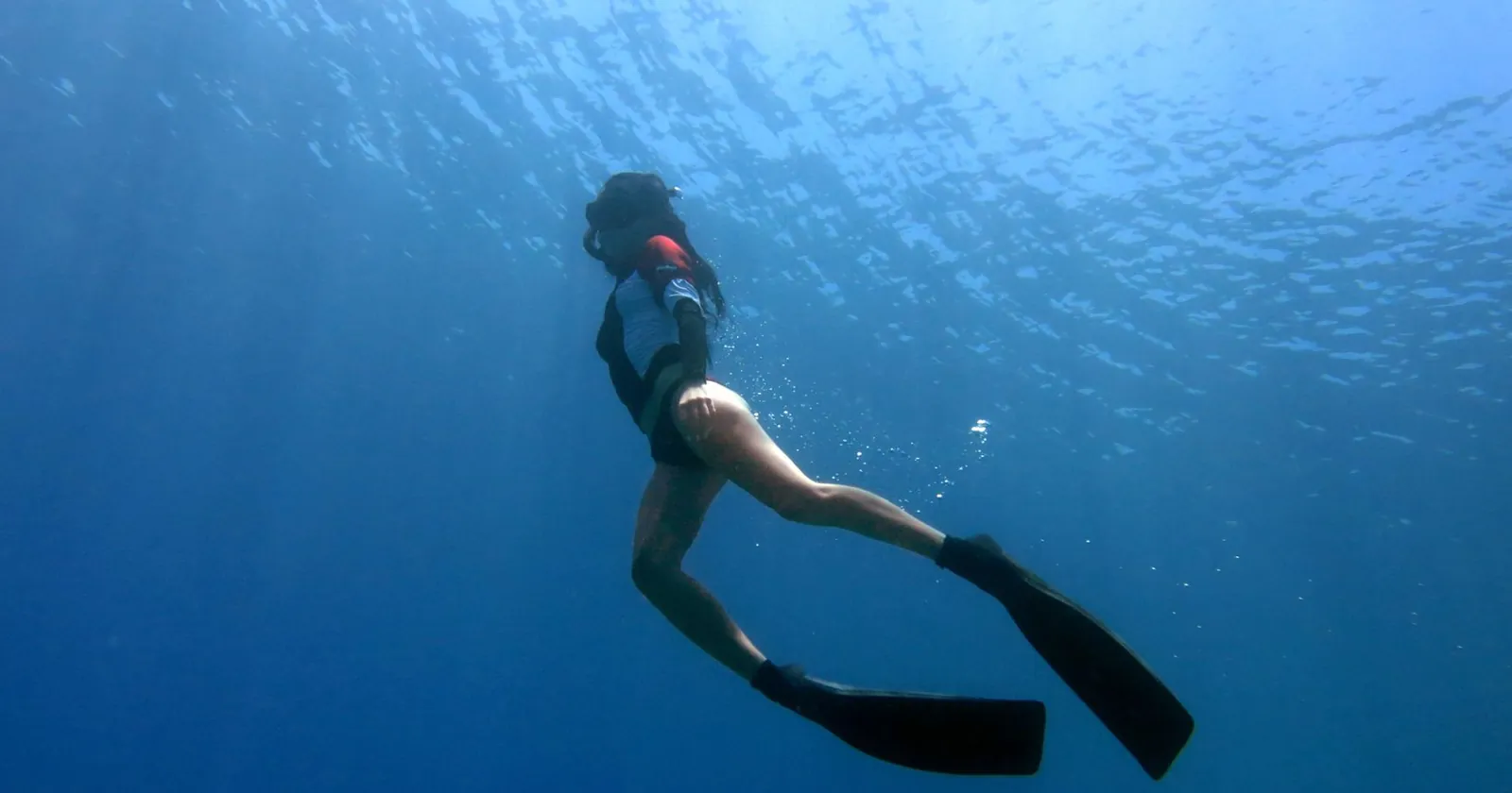 Freediver descending calmly beside a reef