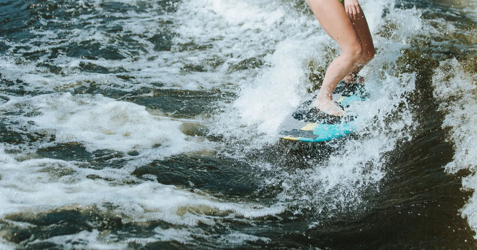 Wakesurfer riding the wake behind a boat without a rope