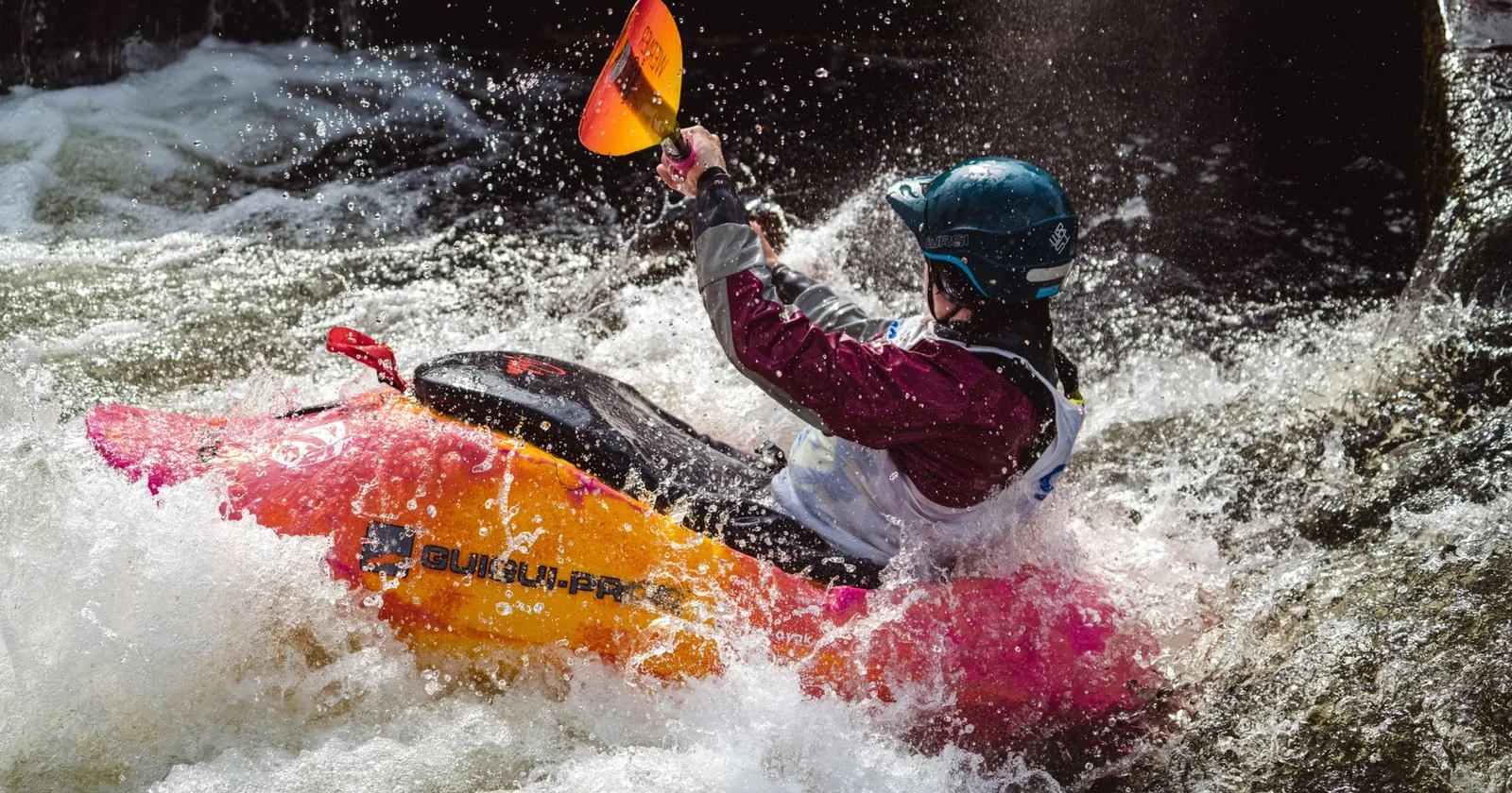 Whitewater kayak, paddle, helmet and buoyancy aid on a riverbank