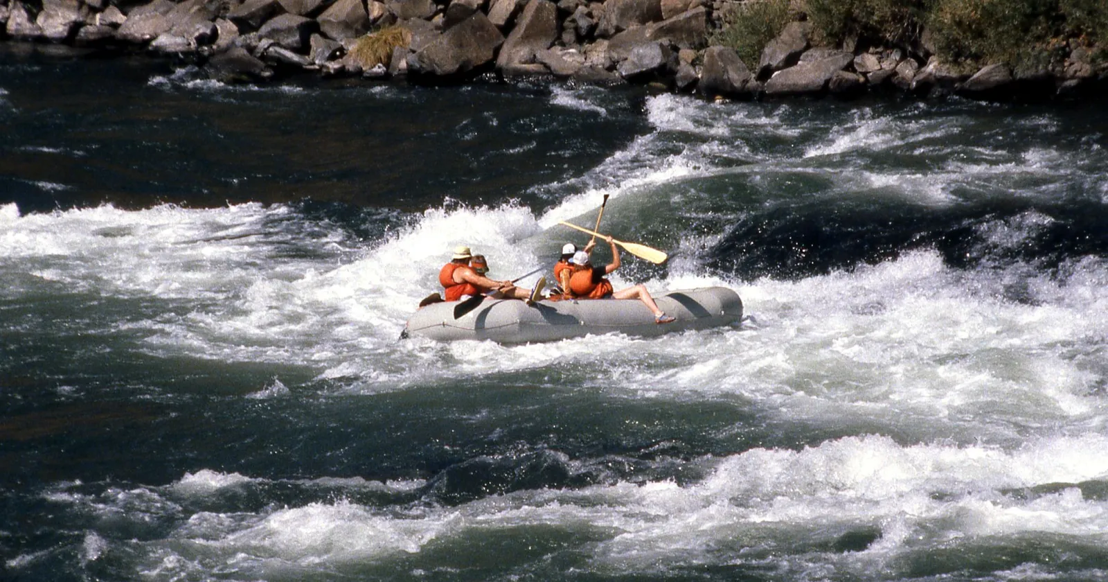 Team paddling an inflatable raft through whitewater rapids
